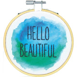 Finished product, Hello Beautiful written in dark thread on blue and green and white fabric. Hello Beautiful Embroidery kit with thread, hoop, fabric, needle, instructions