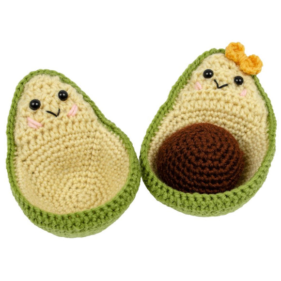 Avocado crochet kit finished result with two halves of avocados with faces, one has a pit and a bow